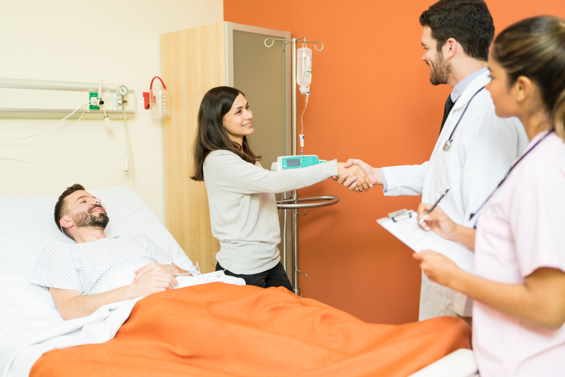 Woman Shaking Hands With Doctor While Standing By Patient